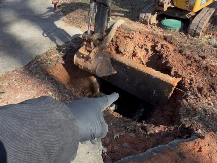 Mini-excavator uncovering a buried septic tank for a real estate inspection