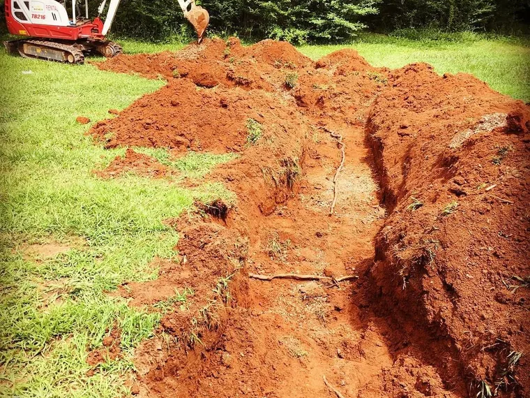 Mini-excavator and a fresh repair trench across a lawn